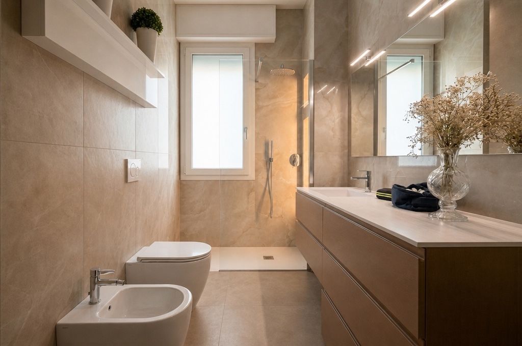 Bagno ristrutturato con rivestimento effetto marmo beige, doccia a filo pavimento e mobile sospeso